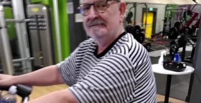 Image shows Duncan using an exercise bike in the gym