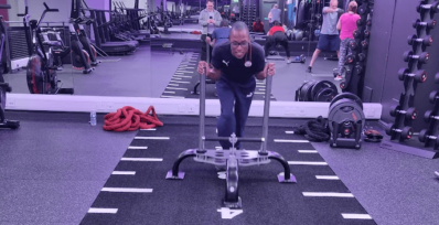 Image shows man pushing a prowler at the gym